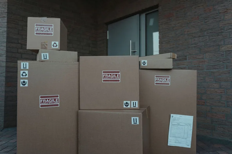A stack of cardboard delivery boxes piled at a building's front door