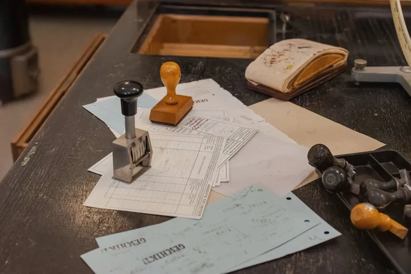 Rubber stamps and official forms stacked on a dark wood bureaucratic desk