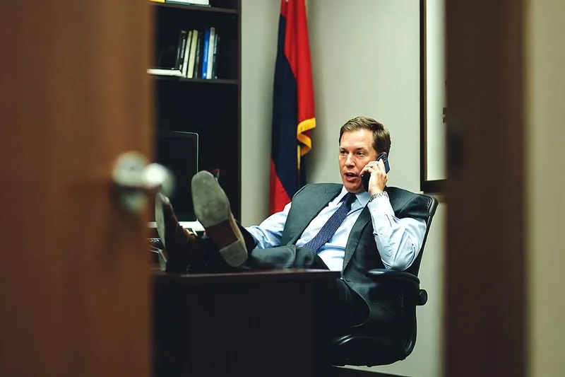 Candid phone photo of a man in a suit on a phone call in a government office.